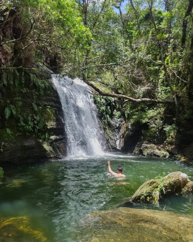 Visitante aproveita as águas cristalinas da Cachoeira da Jandira, cercada por vegetação exuberante no Complexo da Serra Grande.