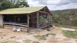 Área rústica de apoio e bar com varanda coberta e bancos de madeira, localizada próxima à Cachoeira da Pedra Furada.