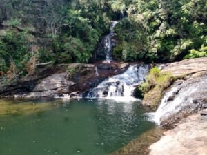 Vista frontal da Cachoeira da Pedra Furada com várias quedas d’água cercadas por vegetação e poço de águas cristalinas.