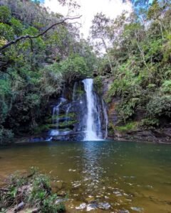 Vista da Cachoeira da Serra Grande em Luminárias, MG, destacando a queda d'água cercada por densa vegetação.