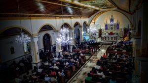 Interior da Igreja Matriz de Nossa Senhora do Carmo, com altar principal durante celebração.
