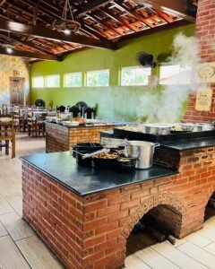 Detalhe do fogão a lenha com alimentos prontos, fogo aceso e variedade de pratos típicos mineiros.