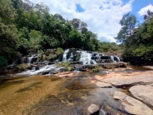 Cascata da Cachoeira da Libélula fluindo suavemente sobre rochas, típica do relevo do Complexo do Mandembe.