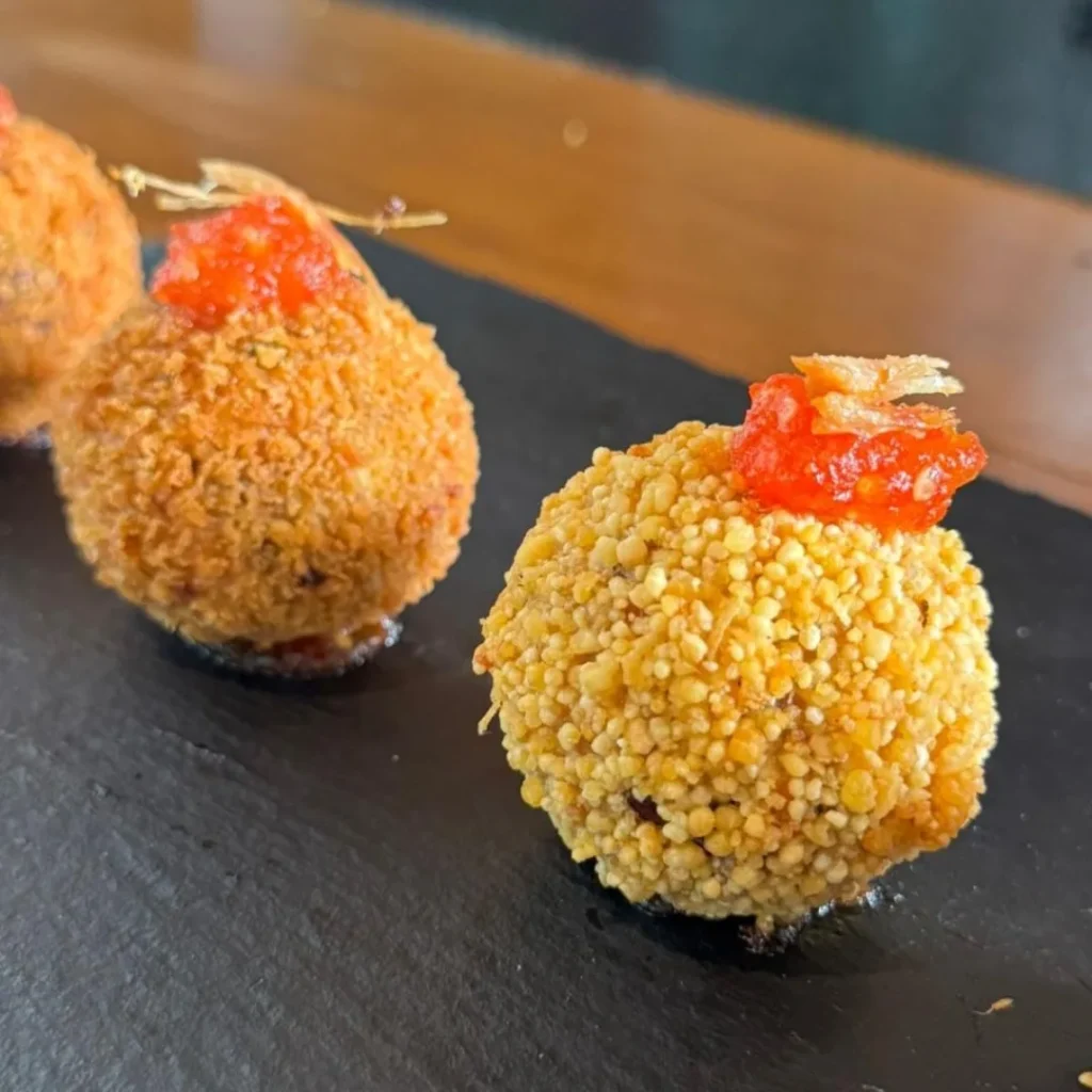 Luminárias recebe estudantes do UniBH em parceria com Le Cordon Bleu em projeto gastronômico e cultural 2 Detalhe do Mini Arancini de Macadame, com recheio de carne de lata e empanado com uarini, finalizado com geleia de pimenta. Uma criativa homenagem ao famoso Macadame de Luminárias.