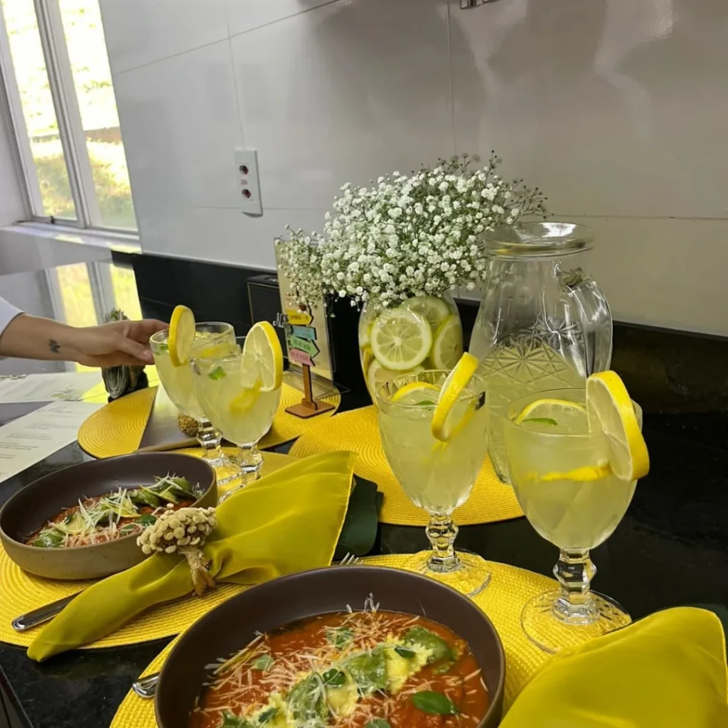 Luminárias recebe estudantes do UniBH em parceria com Le Cordon Bleu em projeto gastronômico e cultural 5 Detalhe da mesa com os pratos e o refrescante Lemoni Spritz, parte do menu criado pelos estudantes. O ambiente luminoso e a atenção aos detalhes são evidentes.